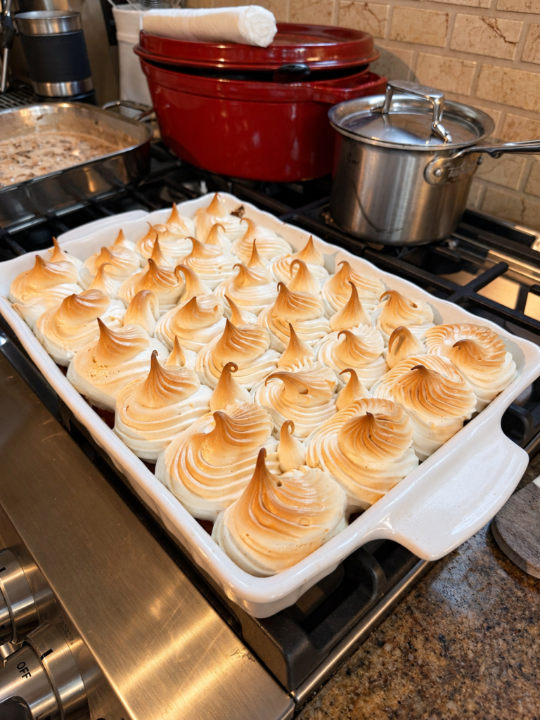 Maple meringue sweet potato casserole with toasted piped meringue peaks in a white baking dish