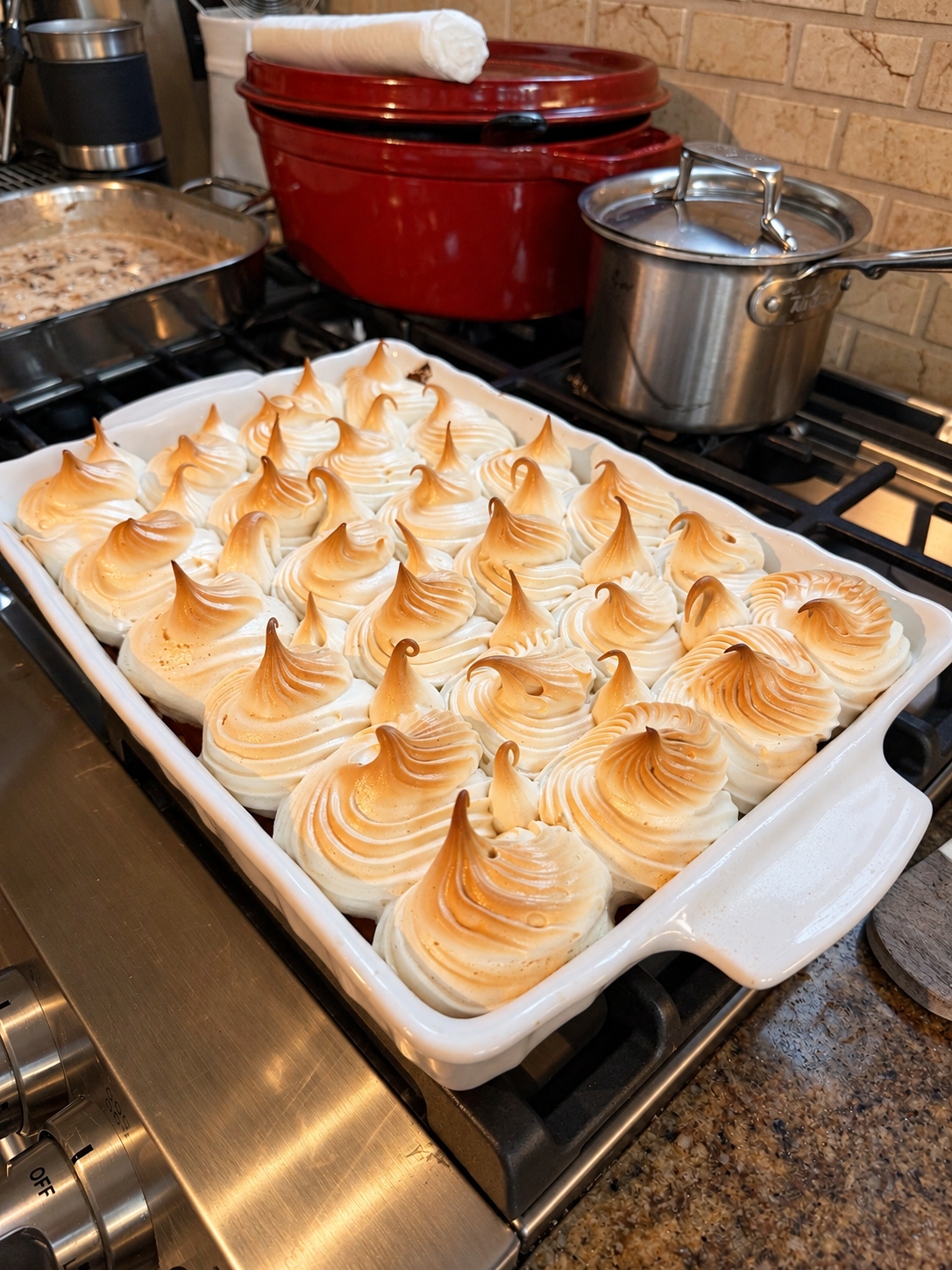 Maple meringue sweet potato casserole with toasted piped meringue peaks in a white baking dish