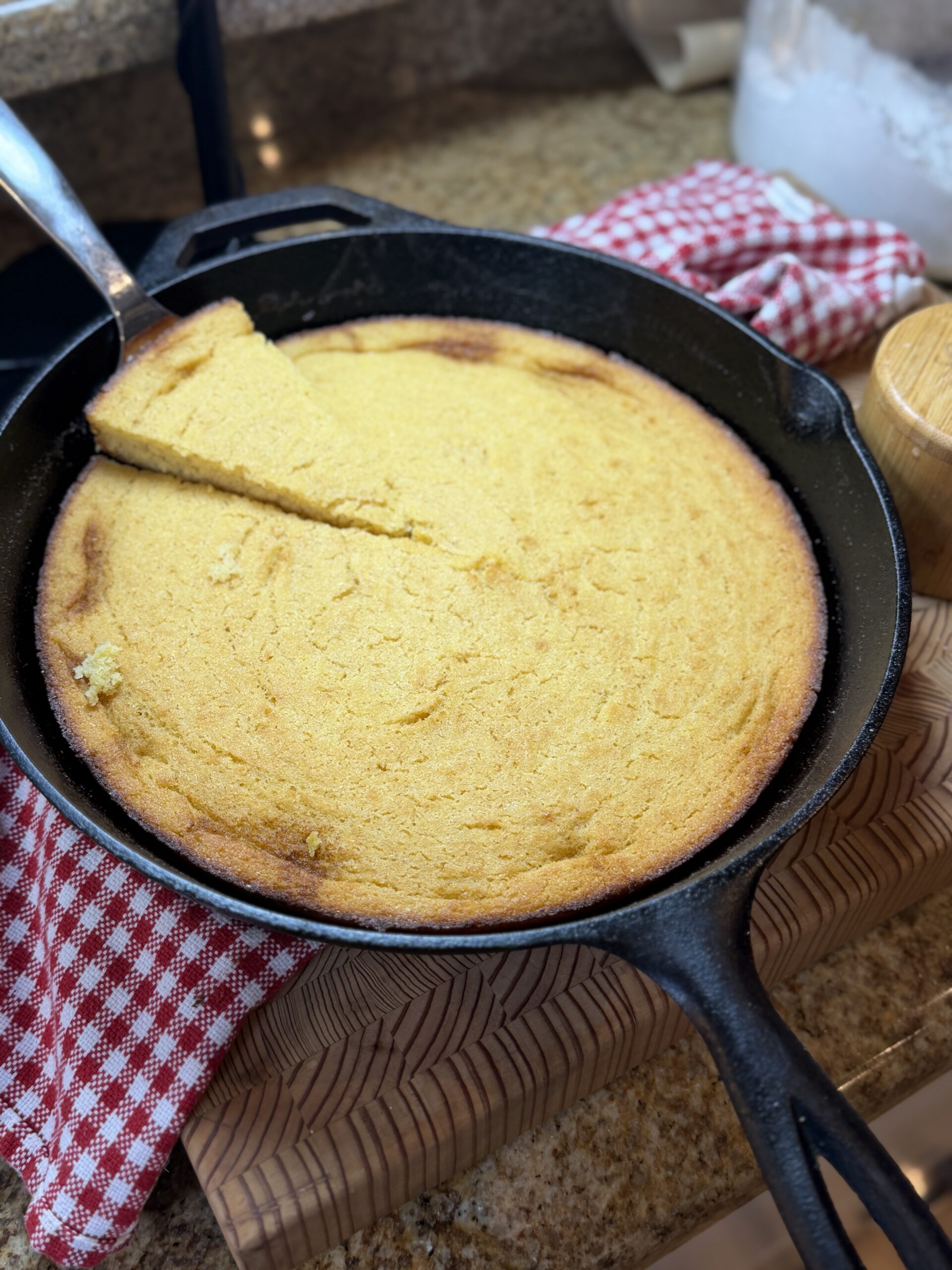 Naturally gluten-free cornbread in a cast iron skillet with one slice lifted out