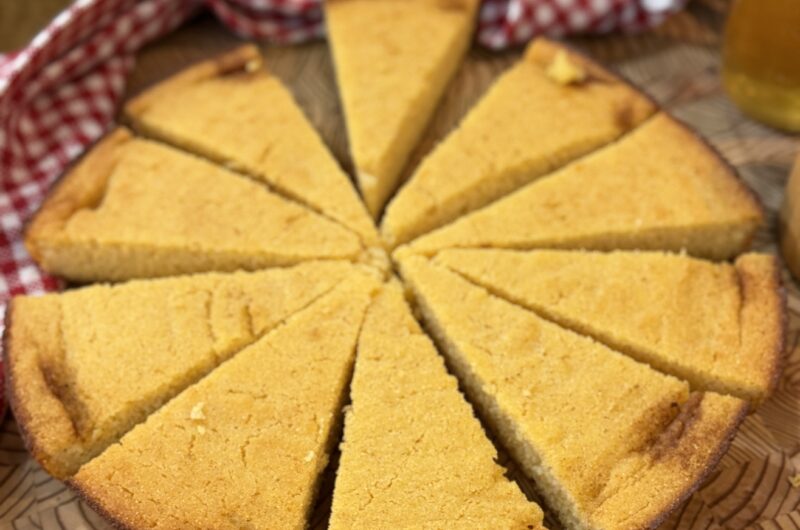 Gluten-free brown butter skillet cornbread sliced into wedges on a wooden board