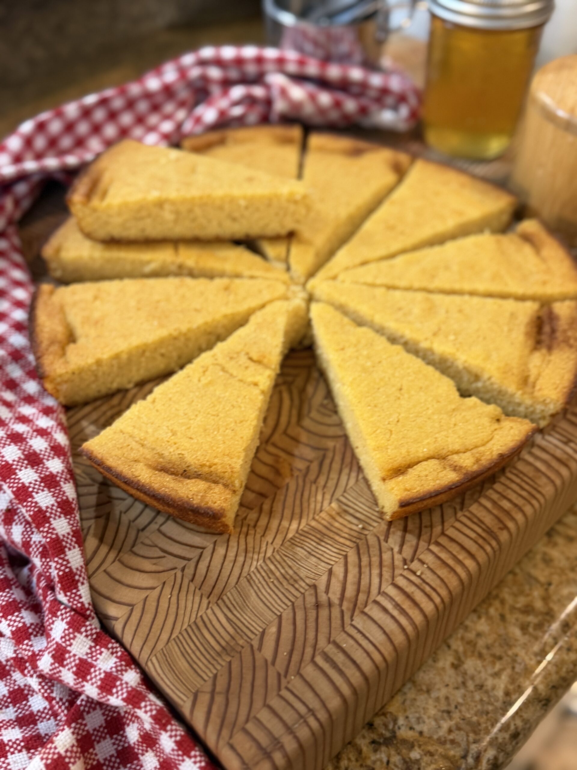 Sliced gluten-free skillet cornbread on a cutting board with a red gingham towel