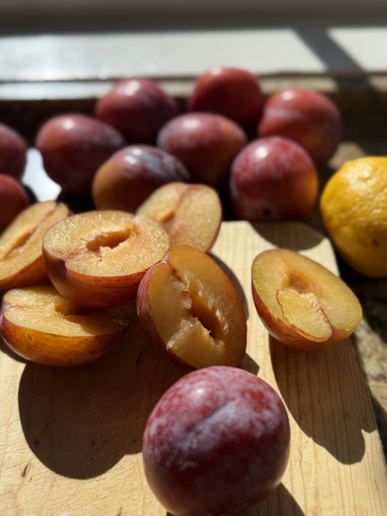 Halved and pitted plums on a cutting board