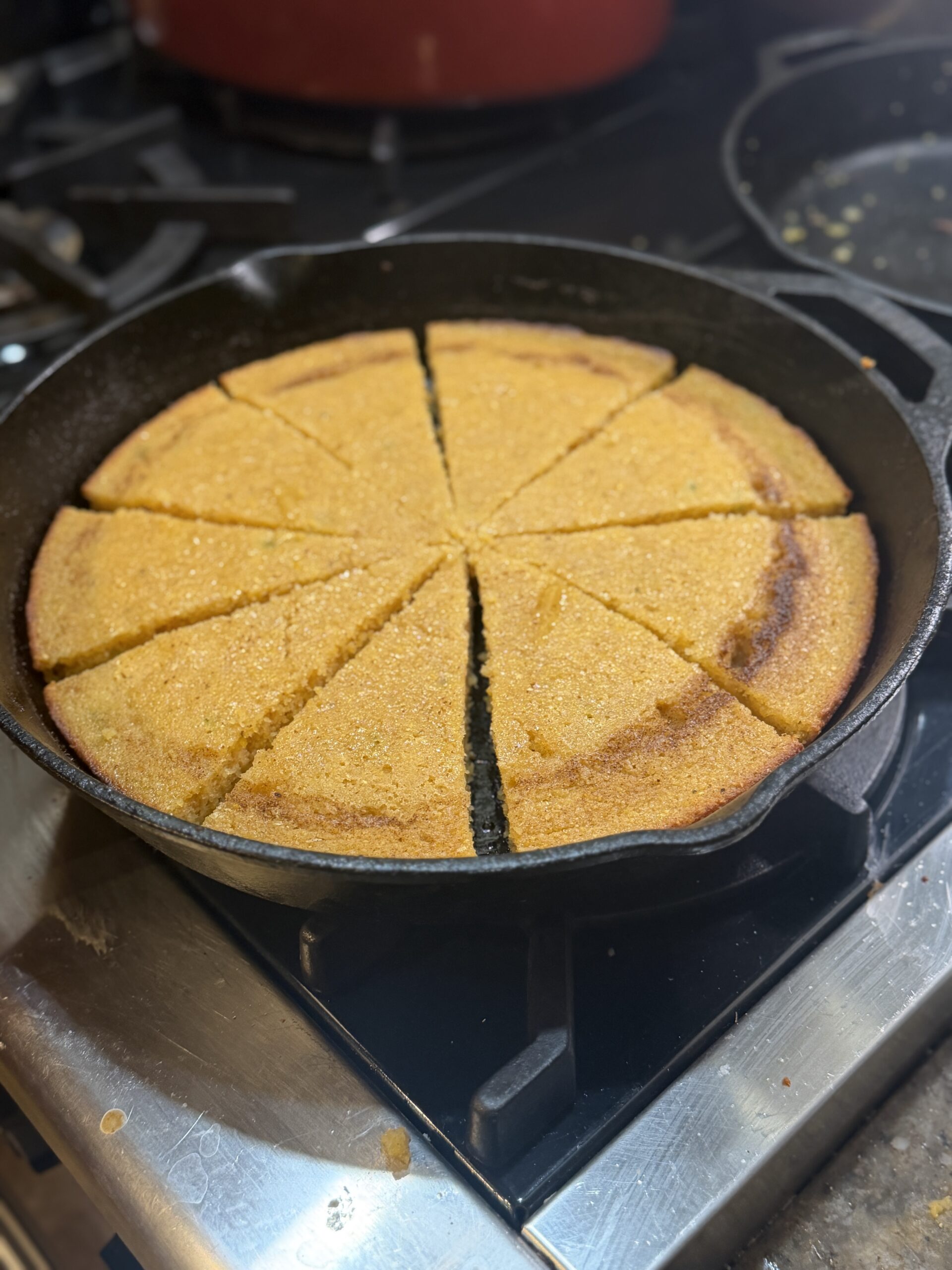 Gluten-free cornbread cut into wedges in a cast iron skillet on the stove